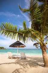Fototapeta na wymiar Chairs and parasol at tropical beach