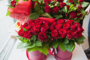 Beautiful bouquets of red roses in gift box, on white window sill