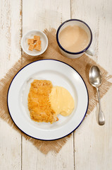 british apple crumble with custard on enamel plate