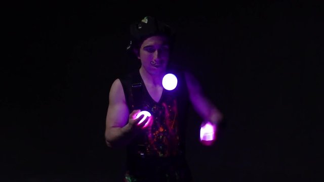 Juggler showing tricks with light balls in the whole dark.Close up.Slow motion