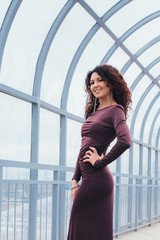 Fototapeta na wymiar Beautiful curly-haired woman in a long dress on a light background