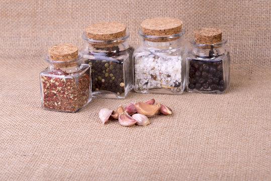 fresh garlic surrounded by containers with herbs