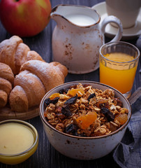 Breakfast table with granola, croissants, apple, coffee, juice