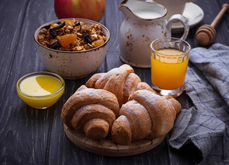 Breakfast table with granola, croissants, apple, coffee, juice