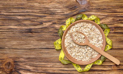 wooden plate with oat flakes and measuring tape on the table