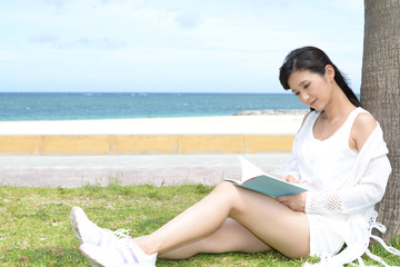 Fototapeta na wymiar 沖縄の海岸で寛ぐ女性