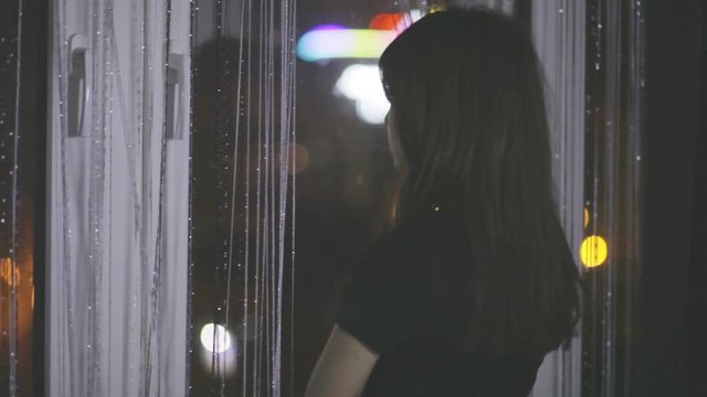the girl at the window sad, waiting for night, it seemed that she heard something that beautiful flare out the window
