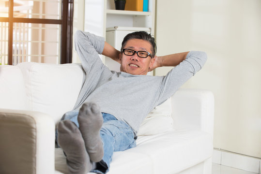 Asian Senior Man Relaxing On Sofa At Home