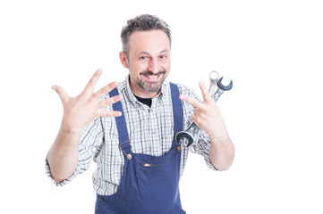 Fototapeta na wymiar Cheerful handsome mechanic with wrench showing or counting seven