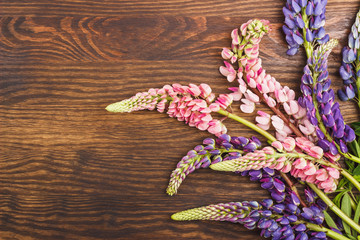 Naklejka premium Violet and pink lupinus on the wooden board
