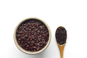 gruel (dark violet rice) in ceramic bow and wooden spoon isolated on white background (top view)