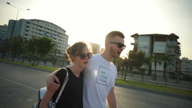 young couple wearing sunglasses going along the road slow motion