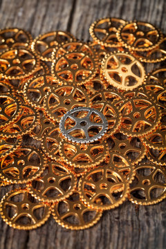 Closeup of metallic cogwheels pile, on wooden surface