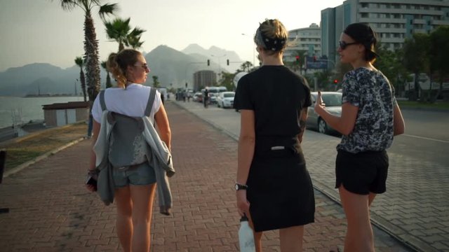 back view of three girls walking in a resort town slow motion
