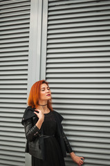 Obraz premium Style girl walks through the darl wall in black jacket and dress. Text place
