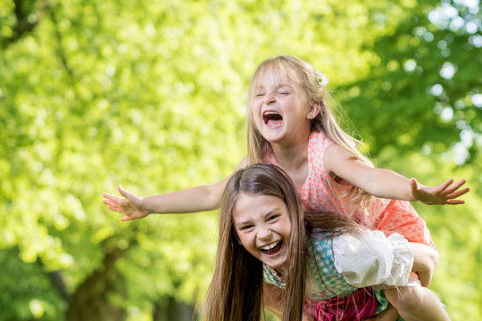 Gro&szlig;e Schwester nimmt kleine Schwester Huckepack