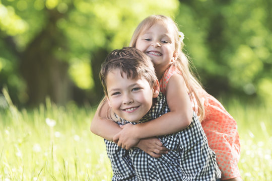 Junge und M&auml;dchen tollen auf Sommerwiese und sind gl&uuml;cklich