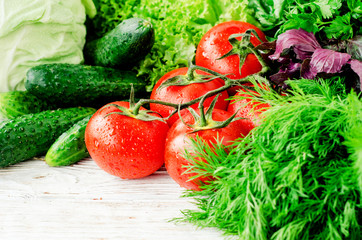 
Fresh juicy ripe summer useful vegetables and greens, red tomatoes , cucumbers , cabbage , lettuce , basil , parsley , dill and salt and spices on a wooden background