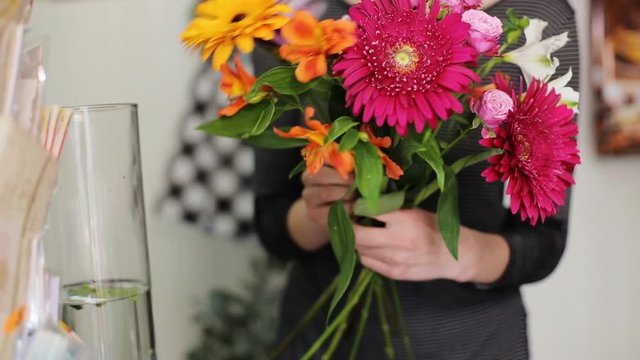 A woman working as a florist making bouquet in the store.