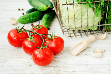 
Fresh juicy ripe summer useful vegetables and greens, red tomatoes , cucumbers , cabbage , lettuce , basil , parsley , dill and salt and spices on a wooden background