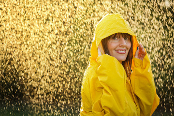 Portrait of happy woman wearing yellow raincoat enjoying the rain.