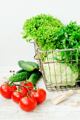 
Fresh juicy ripe summer useful vegetables and greens, red tomatoes , cucumbers , cabbage , lettuce , basil , parsley , dill and salt and spices on a wooden background