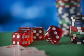 Red dice rotates in the air, casino chips, cards on green felt