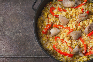 Rice with vegetable and chicken in the pan on the metal background top view