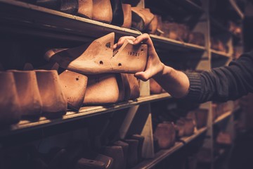Various of vintage wooden shoe lasts in a row on the old shelves.