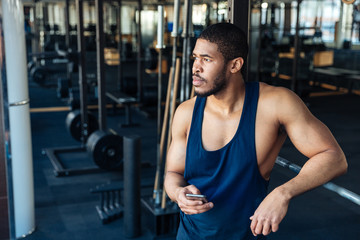 Fototapeta premium Afro american bodybuilder guy holding smartphone