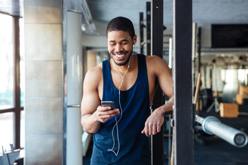 Fototapeta na wymiar Fitness man using smartphone in the gym