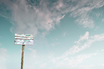 Blank worn wooden sign on cloudy sky