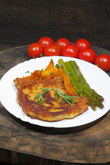 Cutlet with potato wedges, tomatoes, green asparagus, garnished