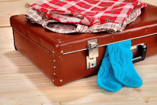 Suitcase, shirts and socks on wooden background