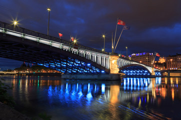 Cityscape: illuminated bridge over the Rhone river in Lyon at dusk.