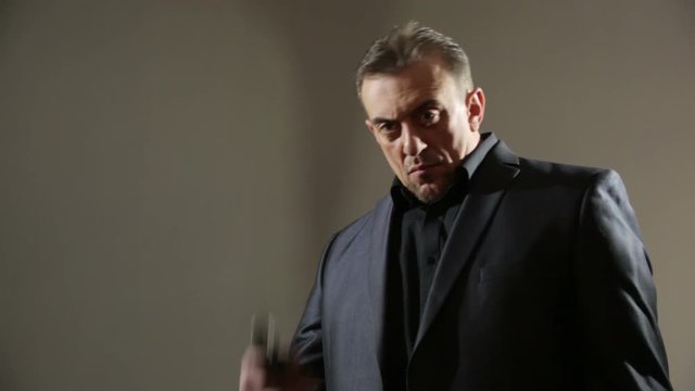 Businessman Pointing Hand Gun. gangster threatens gun. a brutal man in a business suit. aggressive gestures