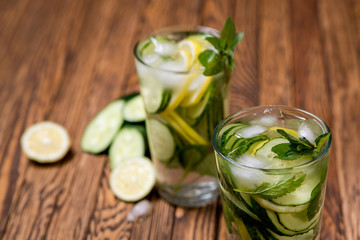 Fototapeta na wymiar Water with lemon, mint and cucumber on wooden background. Water Detox.