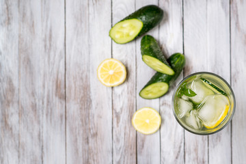 Water with lemon, mint and cucumber on wooden light background. Water Detox. Top view.