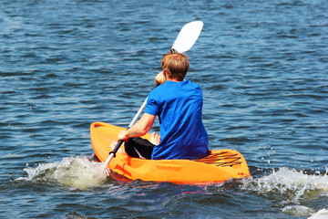 Man rowing a kayak across the blue sea