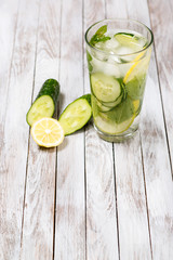 Water with lemon, mint and cucumber on wooden light background. Water Detox.