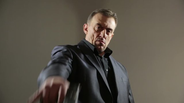 Businessman Pointing Hand Gun. gangster threatens gun. a brutal man in a business suit. aggressive gestures