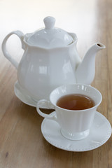 Hot black tea in white cup set on wooden table