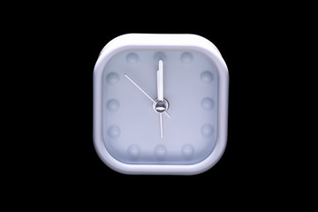 Twelve o'clock on white alarm clock on black background
