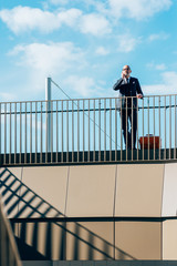 Middle-age contemporary businessman leaning on a handrail talking smart phone - work, business, conversation concept