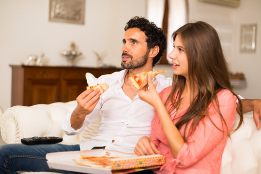 Couple Watching Tv And Eating Pizza