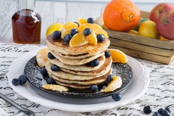 Stack of morning pancakes - healthy breakfast with maple syrup, fresh blueberries and oranges