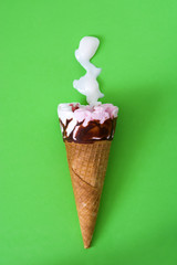 Strawberry ice cream cone on green background
