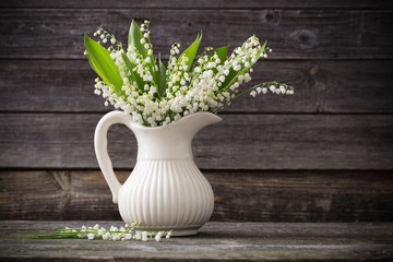 Lilly of valley in vase on wooden table