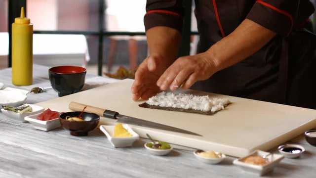 Man's hands make sushi. Male cook working with rice. Special guest at cooking show. Professional gets the work done.