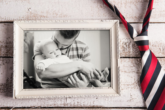 Fathers day composition. Picture frame, photo, tie. Wooden backg